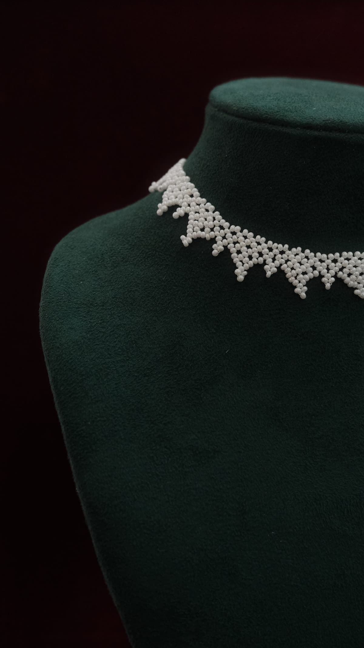 The Lace Choker in Pearl, hand-woven glass seed beads on a green velvet bust